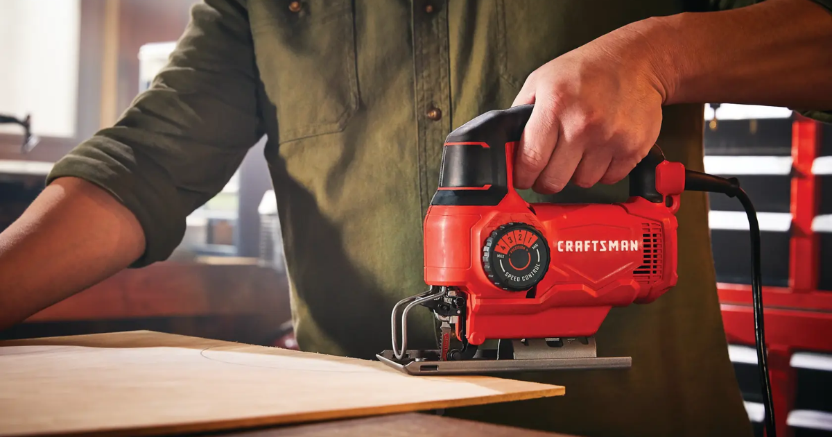 A Craftsman CMES612 corded jigsaw being used to cut sheet material, with the numbered speed control dial on the body and the power cable visible behind