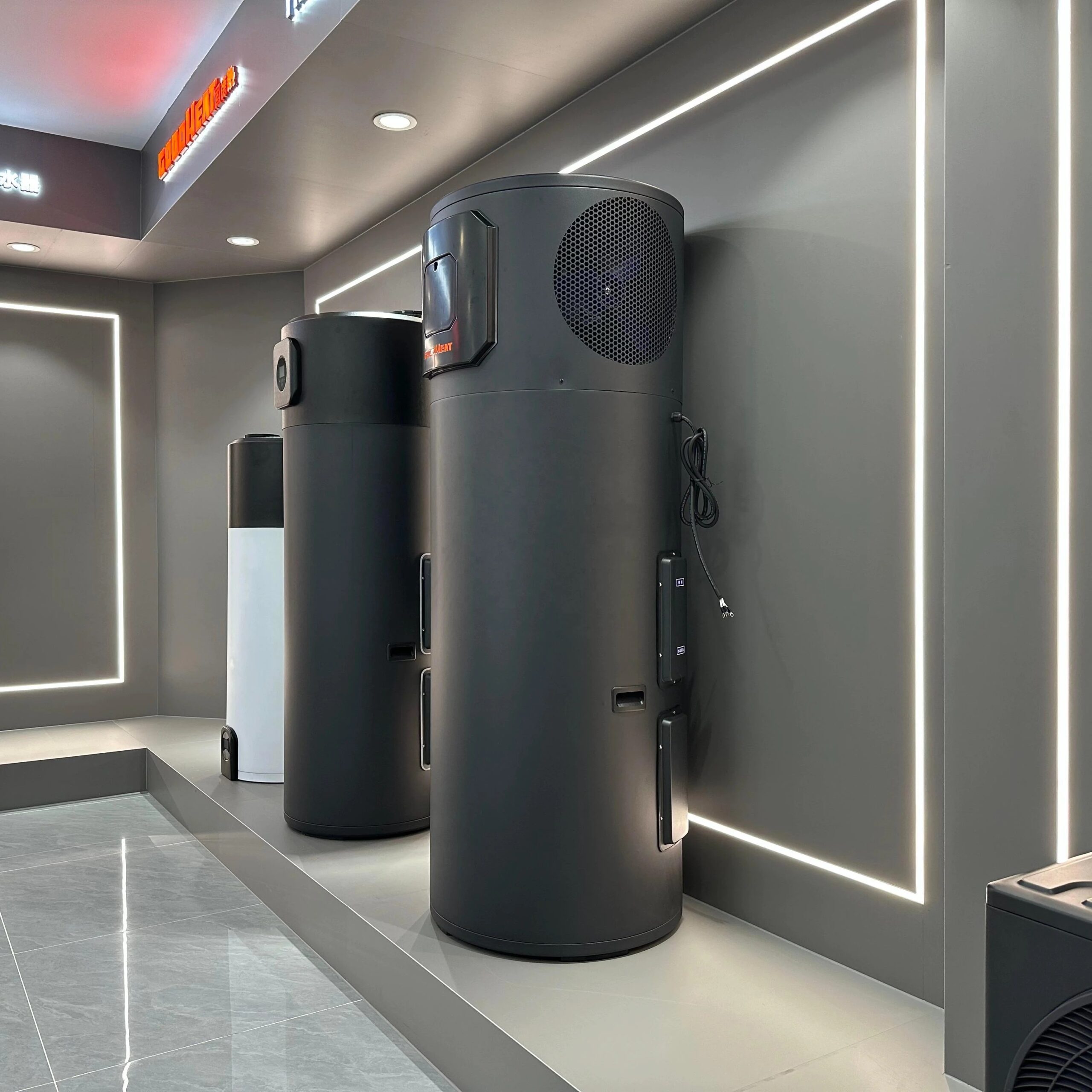 Monobloc heat pump water heaters on display, each with the fan and compressor built into the top of the cylindrical tank body