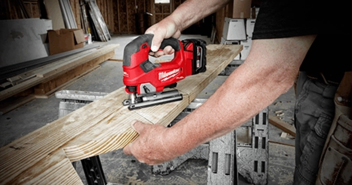 A Milwaukee M18 FUEL 2737 cordless jigsaw with battery fitted, cutting along a timber board supported on sawhorses at a framing site