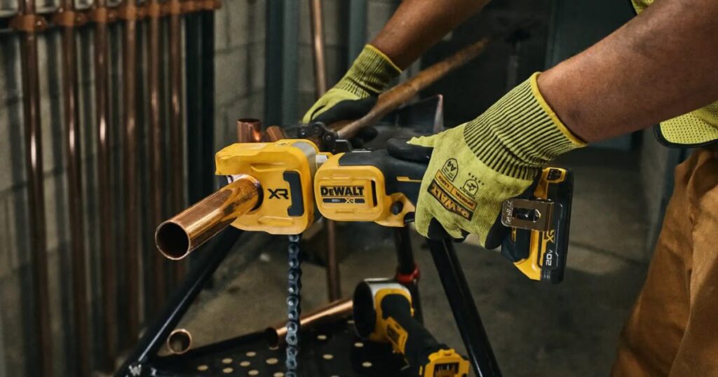A DeWalt 20V MAX XR cordless press tool crimping a copper pipe fitting, operated in cut-resistant gloves at a pipe stand