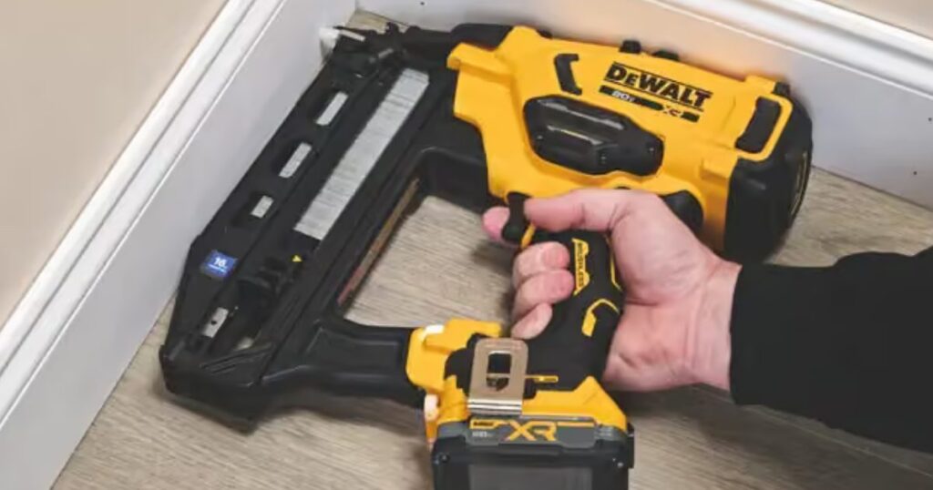 A DeWalt 20V MAX XR cordless 16-gauge straight finish nailer held against white skirting board on a wood floor