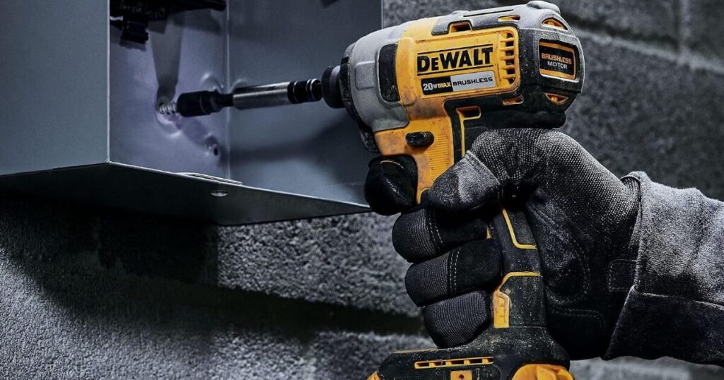 A gloved hand driving a fastener into a steel bracket on a concrete block wall with a DeWalt 20V MAX brushless impact driver