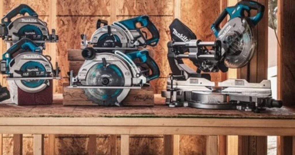Several Makita cordless circular saws and a sliding mitre saw lined up on a timber bench against an OSB wall