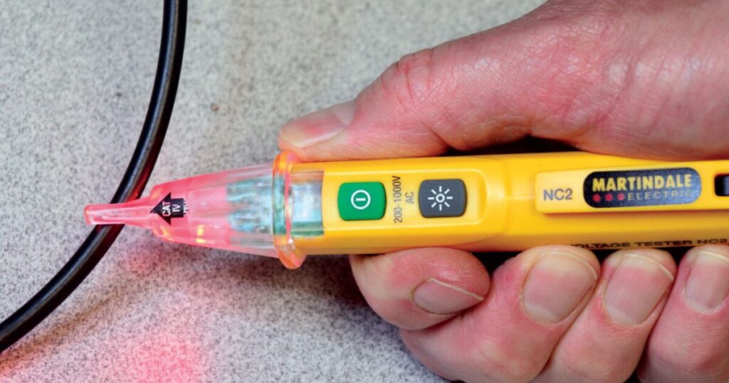 Close-up of a Martindale NC2 voltage tester glowing against a cable, with the CAT IV rating and 200 to 1000V AC range printed on the body