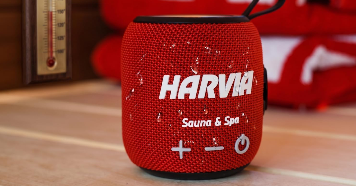 Red Bluetooth sauna speaker with water droplets on its fabric shell, demonstrating waterproof design
